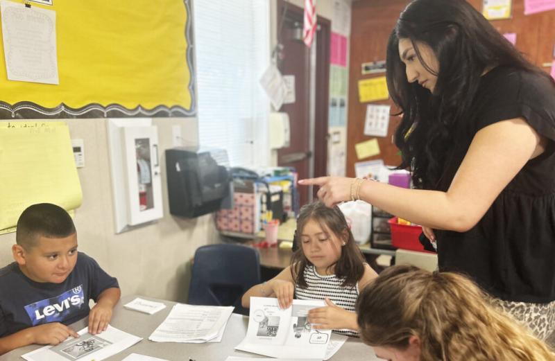 During small group reading instruction, AmeriCorps member Valerie Caballero reminds third graders in Porterville Unified to use their fingers to follow along as they read a passage.