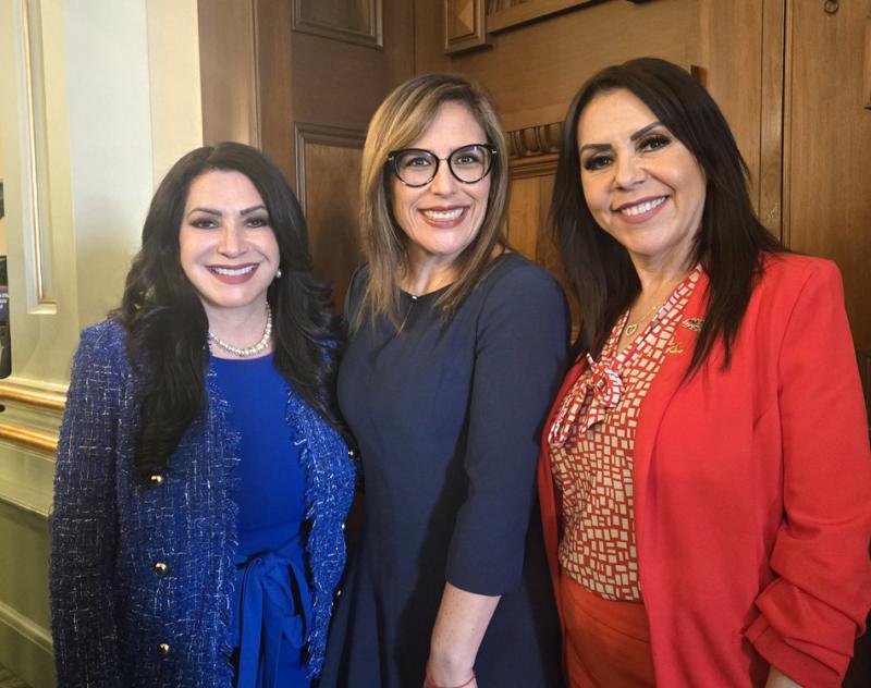 Senator Susan Rubio, actress Angélica Vale, and Assemblymember Blanca Rubio smile together inside the California State Capitol. All three are dressed in bright, professional attire and standing in front of a wood-paneled wall